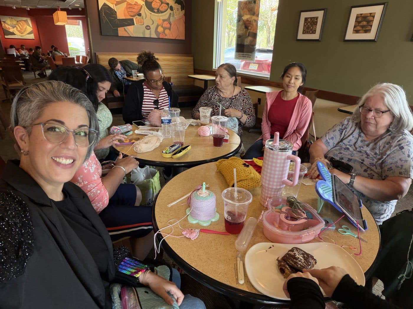 Members crocheting and chatting over drinks at a meetup